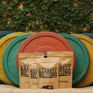 Bags of Barbell Biltong resting against weight barbells